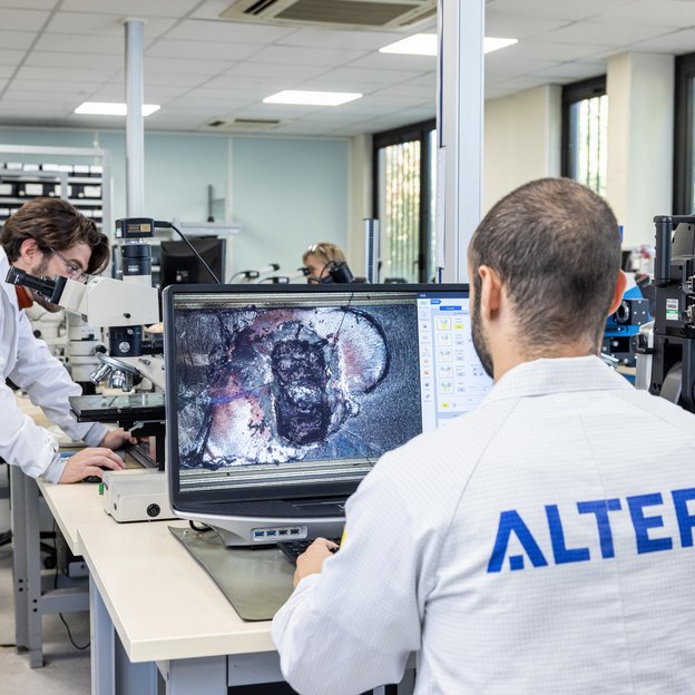 A technician in a lab working on a computer displaying an intricate circuit design.