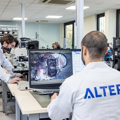 Analyzing Circuit Design in Electronics Laboratory A technician in a lab working on a computer displaying an intricate circuit design.