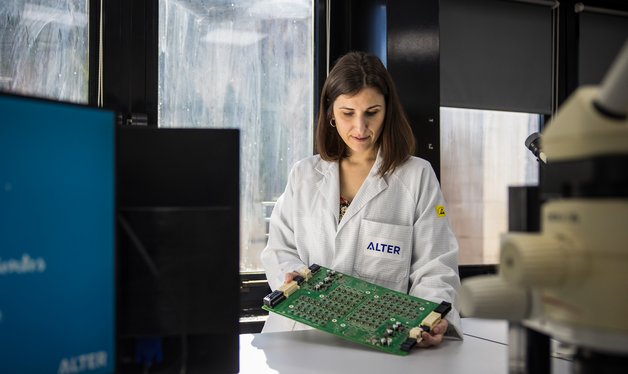 A technician holding printed circuit board in an electronics laboratory.